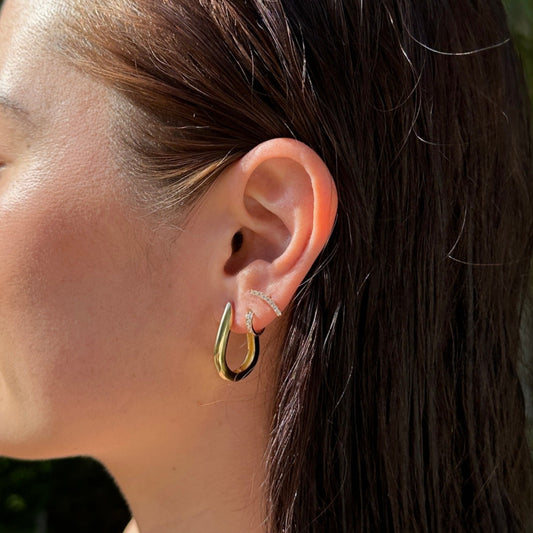 A close up of a female model with brunette hair wearing the 18K Gold Filled Chic U-Shaped Hoop Earrings from a side angle