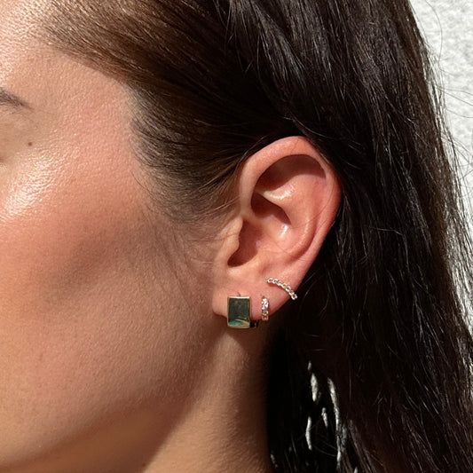 A close up image of a female model wearing the 18K Gold Filled Cube Clicker Earrings from a side angle