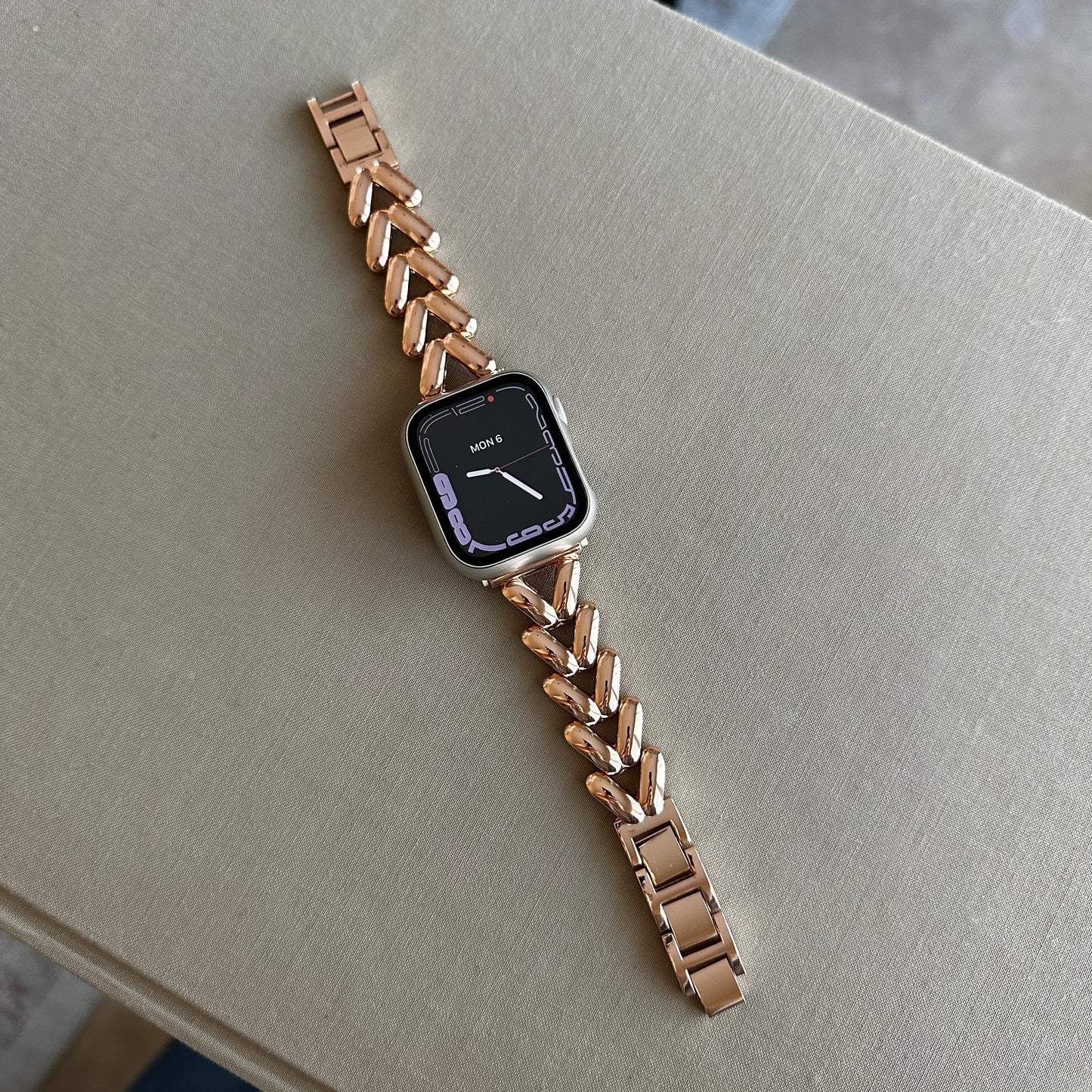 Close up of the Gold-Tone Alloy Link Chain Watch Band Compatible with Apple Watch displayed flat across beige surface