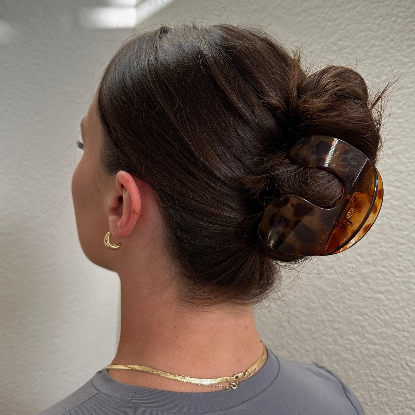 Female model with brunette hair styled in a bun wearing the Jelly U-Shaped Hair Clip in Tortoise showing the back of her head