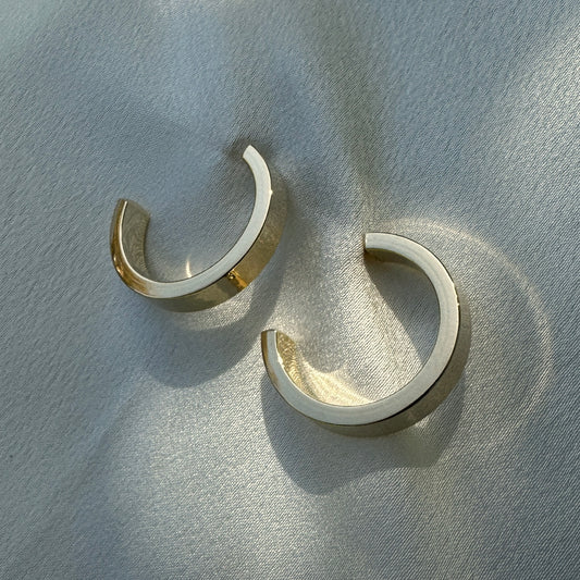 A close up product image of the 18K Gold Filled Sleek Semi Hoop Earrings displayed on white satin fabric
