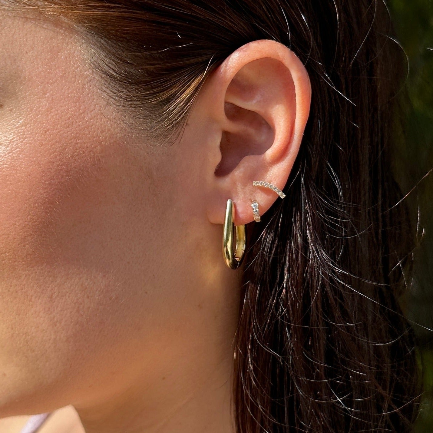 Female model with brunette hair wearing the 18K Gold Filled Chic U-Shaped Hoop Earrings showing a close up on her ear