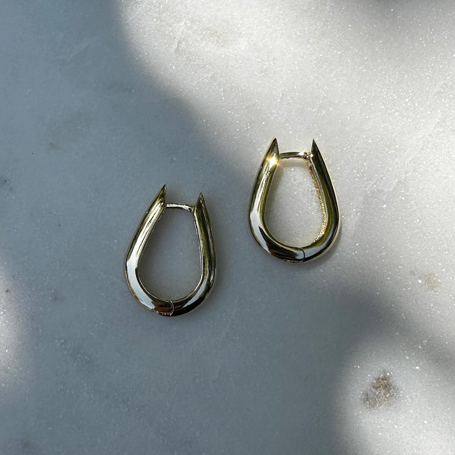 A close up product image of the 18K Gold Filled Chic U-Shaped Hoop Earrings from an above front angle with natural light