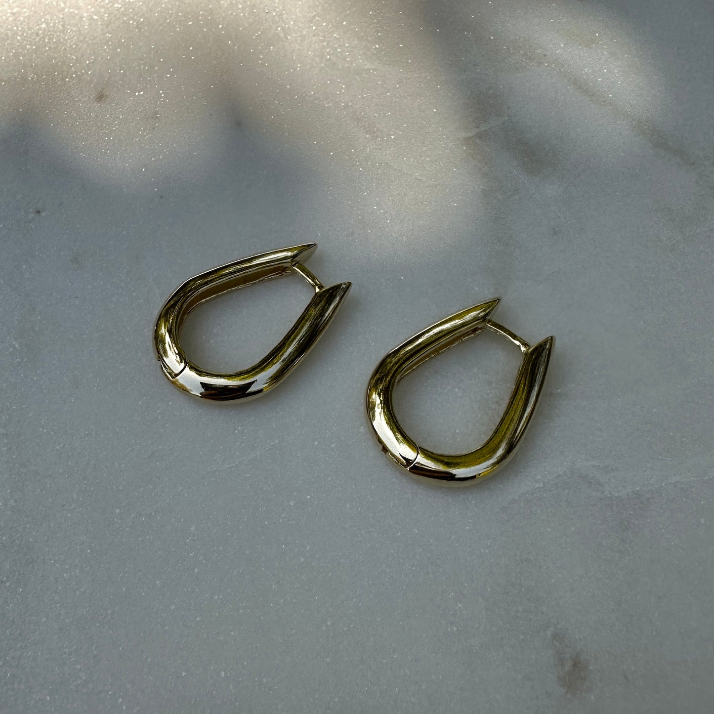 A close up product image of the 18K Gold Filled Chic U-Shaped Hoop Earrings from an above side angle
