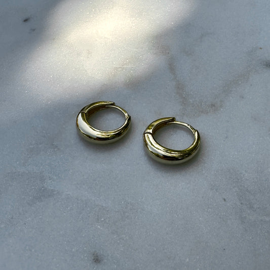 A pair of the 18K Gold Filled Classic Clicker Hoop Earrings on white marble surface from front angle