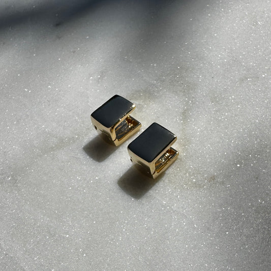 A close up image of the 18K Gold Filled Cube Clicker Earrings displayed on sparking marble surface